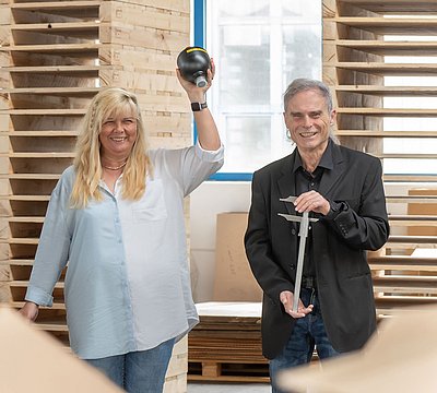 Drei Mitarbeiter schauen in die Kamera und halten eine Konsole, einen Membranspeicher und einen Messschieber