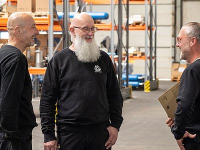 Drei Mitarbeiter unterhalten sich über einen Auftrag im Lager